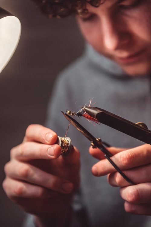 Teenage boy tying fishing flies