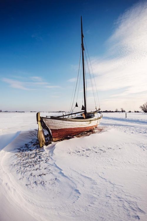 Old wooded boat stranded on land and surrounded by snow