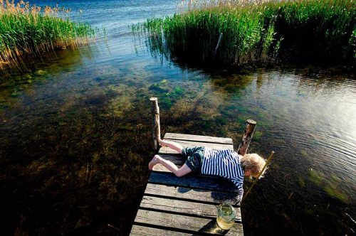 Portrait of a young boy fishing with a net off a jetty into the lake