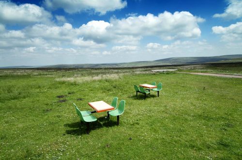 Pair of plastic picnic tables in an odd place at the top of a hill