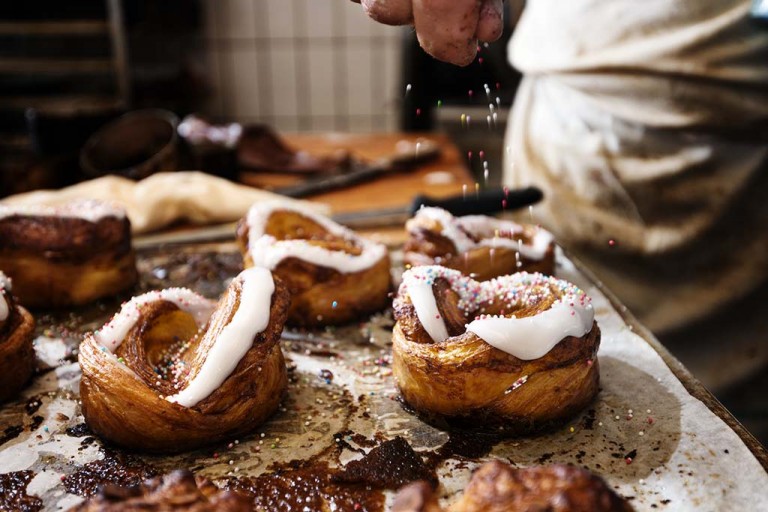 Baker adding sprinkles to a danish pastry