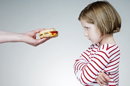 Trying to persuade a child to eat a burger.