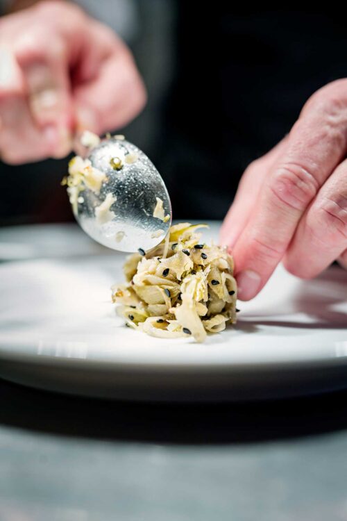 Chef at work preparing a palte of food at the pass.