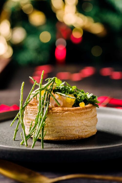 Close-up of seafood stuffed vol-au-vent, made with prawns and crab finished with lemon pearls, samphire and parsley.