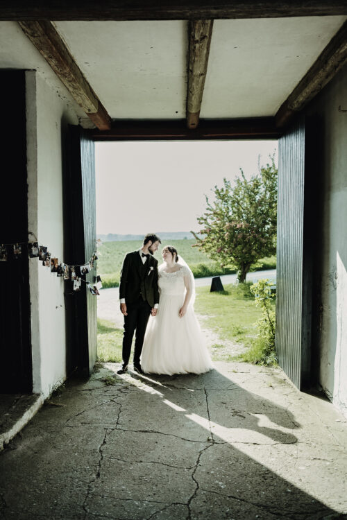 Bryllupsfotograf på Møn: Brudepar i dørindgang på gammel gård, Sydsjælland – bryllupsfotografering.