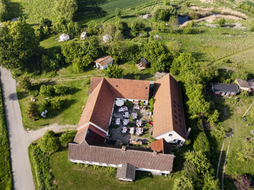 Dronefoto af bryllupsreception i gammel gårds gårdhave på Møn – bryllupsfotograf fanger fest fra luften.