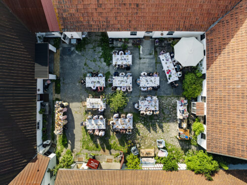 Dronefoto af bryllupsreception i gammel gårds gårdhave på Møn – bryllupsfotograf fanger fest fra luften.